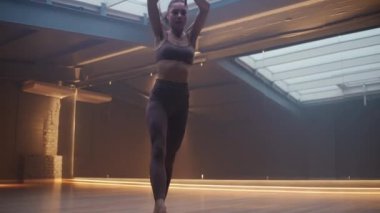 Genç kadın aynalı bir odada esneme hareketleri yapıyor, sportif kadın yoga öğeleriyle esneme hareketleri yapıyor, güzel bir dans..