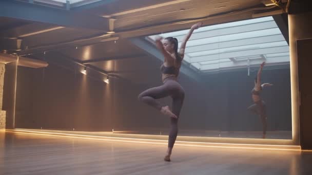 苗条身材的女人在一个有镜子的房间里做伸展运动 而女人则在一个有瑜伽元素的房间里做伸展运动 一个美丽的舞蹈 — 图库视频影像