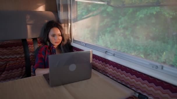 在笔记本电脑上工作的亚裔女性 坐在车里 在大自然中做远程工作 在野营车上的夕阳西下的肖像 — 图库视频影像