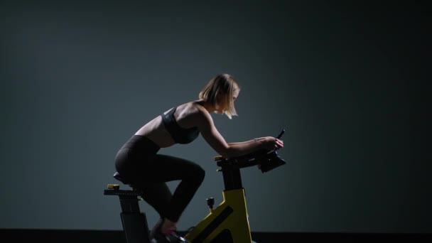 Mulher Desportiva Está Envolvida Uma Bicicleta Exercício Moderno Realiza Treinamento — Vídeo de Stock