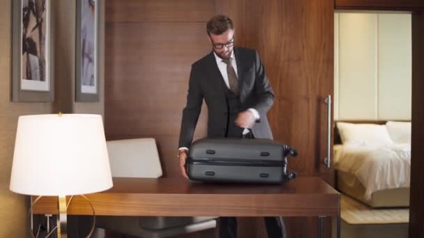 ベラルーシ ミンスク 10月 2019 スーツケース ホテルの部屋のインテリアから物事を取るスーツの優雅なビジネスマン — ストック動画