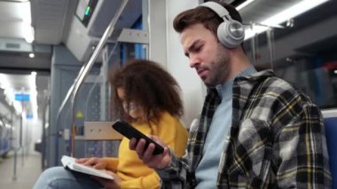 Öğrenciler metroda ders çalışmaya gidiyor, genç adam akıllı telefon kullanıyor ve kablosuz kulaklıkla müzik dinliyor, bir kadın kitap okuyor, toplu taşıma araçları....
