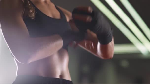 女战士用拳击绷带包着双手 在体育馆里练跆拳道 点燃霓虹灯 — 图库视频影像
