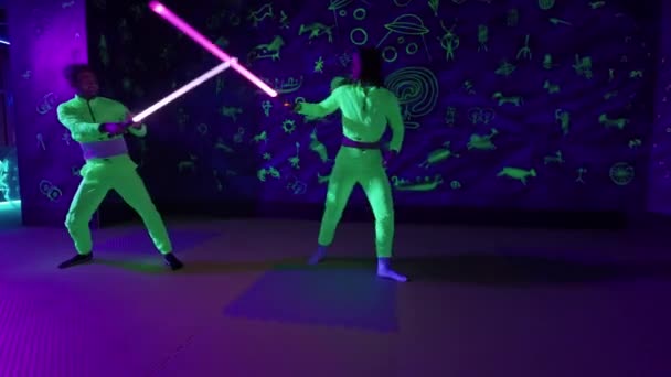 年轻人在霓虹灯游乐园里玩得很开心 一男一女在用光剑 击剑互相争斗 — 图库视频影像