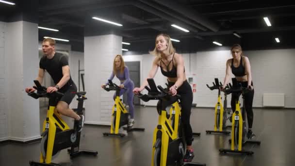 Grupp Människor Engagerade Modern Motionscyklar Utför Aerob Uthållighetsträning Simulatorn Gymmet — Stockvideo