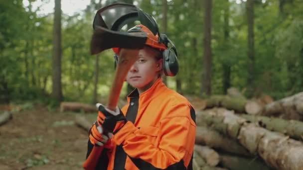 森林里站着一位女伐木工人的画像 一位身穿防护服的年轻专业妇女手里拿着一把斧头 从事森林砍伐方面的工作 — 图库视频影像