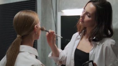 Ceerful kadın makyaj sanatçısı haberleri canlı yayınlamadan önce bir TV sunucusu uyduruyor. Medya etkinliğine hazırlanıyor. Makyöz iş başında..