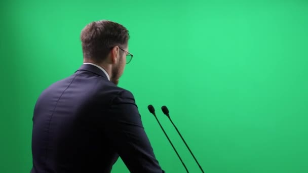 Baksidan Elegant Man Kostym Står Grön Bakgrund Föreläsaren Talar Till — Stockvideo