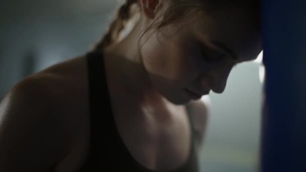 女强人的力量 疲惫的女战士在拳击馆经过艰苦训练后 被压在沙袋上 — 图库视频影像
