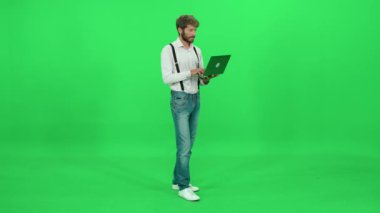 Genç sanat yönetmeni dizüstü bilgisayarda çalışır, çalışır ve dizüstü bilgisayar kullanır, yeşil arka plan, krom anahtar şablonu.