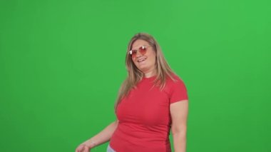 Alışveriş, kırmızı tişörtlü bir kadın kredi kartı kullanarak başarılı alışverişler yapıyor. Büyük boy bir model yeşil arka planda başarılı alışverişlerden hoşlanıyor..