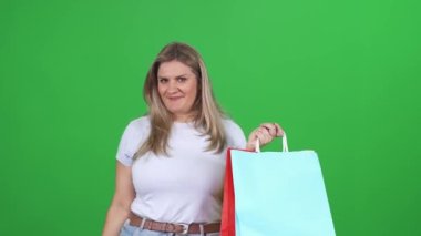 Alışveriş, beyaz tişörtlü bir kadın kredi kartı kullanarak başarılı alışverişler yapıyor. Büyük boy bir model yeşil arka planda başarılı alışverişlerden hoşlanıyor..
