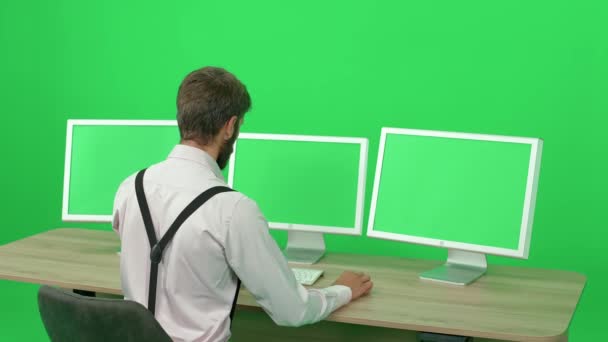 专注于个人电脑上工作的记者 坐在办公桌前 绿色背景 一个在监视器后面工作的人 色键模板 后视镜 — 图库视频影像