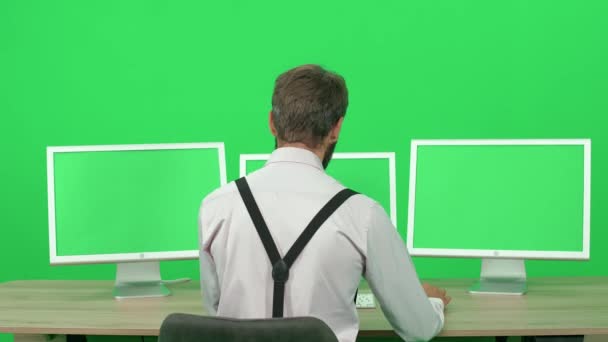 专注的开发人员在个人电脑上工作 坐在办公桌前 绿色背景 一个人在监视器后面工作 色键模板 后视镜 — 图库视频影像