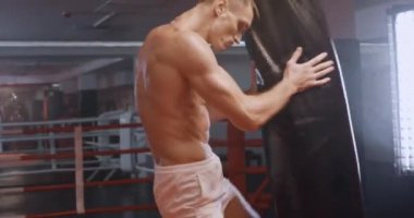 Kickboks, atletik boksör yumruklarını eğitir, kum torbasını döver, boks salonunda antrenman günü, arka ışıklandırma..