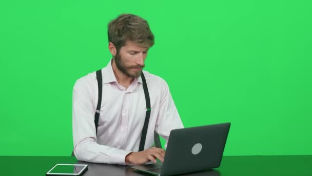专注的开发人员在笔记本电脑上工作 坐在办公桌前 绿色背景 观看演播室电视新闻 彩色键模板 — 图库视频影像