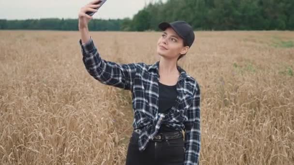 在农村 女农民站在一片黑麦地里 用智能手机给自己拍照 调查植物 — 图库视频影像