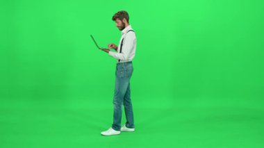 Sanat yönetmeni dizüstü bilgisayarda çalışır, yazı yazar ve çalışır, yeşil arkaplan, krom anahtar şablonu.