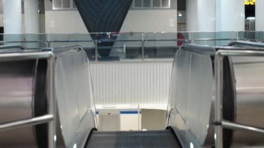 Odaklanmış öğrenci kitap okurken metroda yürüyen merdivene biniyor, genç adam okumak için üniversiteye gidiyor, sınav hazırlığı, yeraltı.