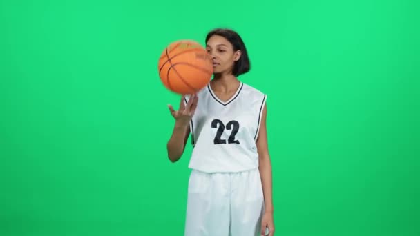 色彩艳丽的黑皮肤女人 篮球运动员把球扔在手中 职业篮球运动员在室内操场上 绿色背景 — 图库视频影像