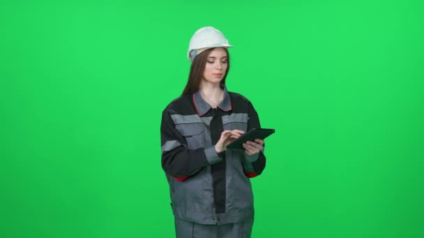 ユニフォームと保護ヘルメットに焦点を当てた女性労働者 技術エンジニアは 緑の背景にスクリーンタブレットを使用し クロメイキーの女性エンジニア — ストック動画