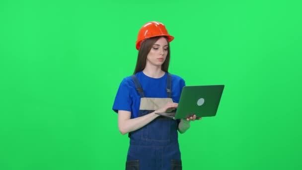ユニフォームと保護ヘルメットに焦点を当てた女性労働者の肖像画 エンジニアは 緑の背景にラップトップを使用し 染色体の女性エンジニア — ストック動画