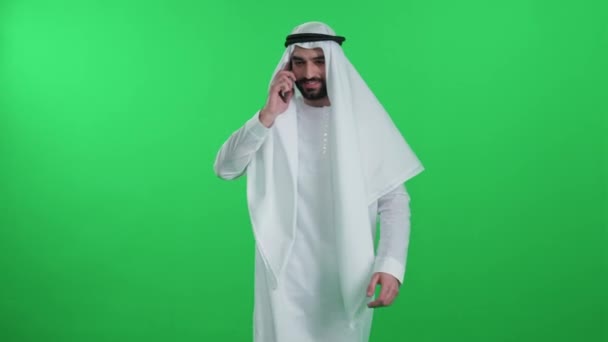 Arab Muž Bílém Rouchu Kráčí Zeleném Pozadí Sobě Kandura Mluví — Stock video