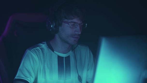 一个全神贯注的男人头戴耳机 玩电子游戏 参加锦标赛的网络运动员 蓝色霓虹灯的画像 — 图库视频影像