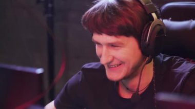 Kulaklıklı genç bir oyuncu, video oyunu oynuyor, oyunda siber sporcu, oyuncular arası iletişim, oyunlar turnuvası.