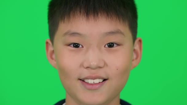 Portrét Veselého Asijského Chlapce Hledícího Kamery Zeleném Pozadí — Stock video