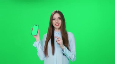 İnternetten alışveriş yapan, tişörtlü genç bir kadın iyi ürünler buluyor ve yeşil arka planda şık bir kadın olan akıllı telefon kullanarak internette başarılı bir alışveriş yapıyor..