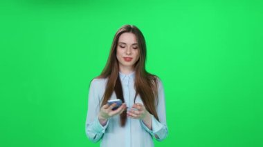 İnternetten alışveriş yapan, tişörtlü genç bir kadın iyi ürünler buluyor ve yeşil arka planda şık bir kadın olan akıllı telefon kullanarak internette başarılı bir alışveriş yapıyor..