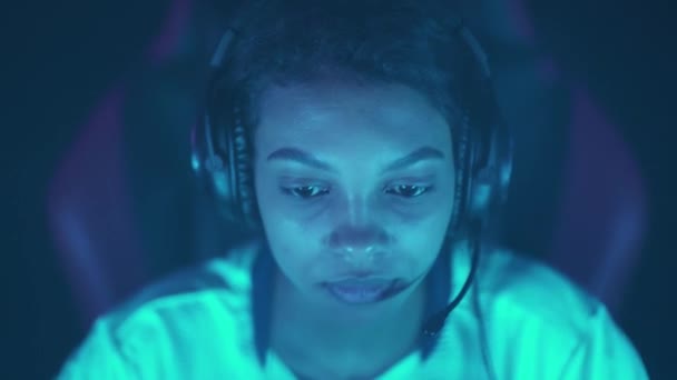 一个专注于耳机的女性游戏玩家的肖像 玩电子游戏 蓝色霓虹灯 — 图库视频影像