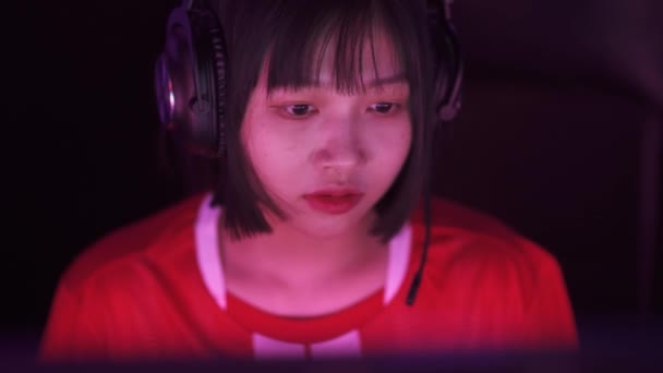 ハンドヘルド ヘッドフォンでアジアの女性ゲーマーの肖像画 ゲームでビデオゲーム サイバースポーツマン プレーヤー間のコミュニケーション チームとしてプレー — ストック動画