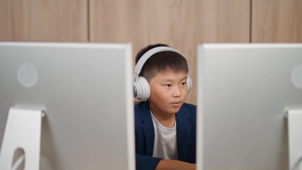 アジアの少年は 自宅で机に座っている間にPcで作業し 10代の少年がモニターの背後でオンラインで働き 研究しています — ストック動画