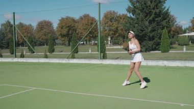 Profesyonel bayan tenisçi raketle topa vuruyor, tenis kortunda antrenman yapıyor, rakiplerine vuruyor, tenis maçında servis yapıyor, 4k süper ağır çekim..