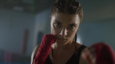 Kadın gücü, bir kadın dövüşçünün portresi savaş pozisyonunda duruyor ve kameraya bakıyor, ciddi bir bakış, 4k ağır çekim..