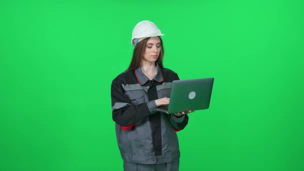 ユニフォームと保護ヘルメットの若い女性労働者 技術エンジニアは 緑の背景にラップトップを使用し クロメイキーの女性エンジニア — ストック動画