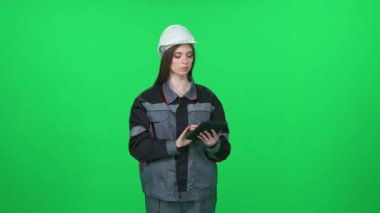 Dijital mühendis, üniformalı ve koruyucu miğferli kadın mühendis, teknik mühendis yeşil arka planda ekran tableti, kromakey üzerinde kadın mühendis..