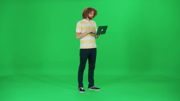 若いアートディレクターは ノートパソコン 外出先のラップトップにタイプするアフロヘアスタイルの男 緑の背景 クロマキーテンプレートで動作します — ストック動画