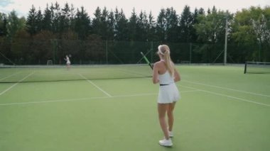 Profesyonel bayan tenisçinin arkadan bakışı topa raketle vuruyor, genç kadın rakiplerine vuruyor, tenis maçında servis yapıyor, 4k yavaş çekim..