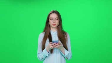İnternetten alışveriş yapan, tişörtlü genç bir kadın iyi ürünler buluyor ve yeşil arka planda şık bir kadın olan akıllı telefon kullanarak internette başarılı bir alışveriş yapıyor..