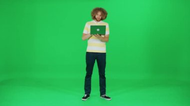 Odaklanmış sanat yönetmeni dizüstü bilgisayarda çalışır, afro saç stili olan bir adam dizüstü bilgisayarda yazar, yeşil arka plan, kroma anahtar şablonu.