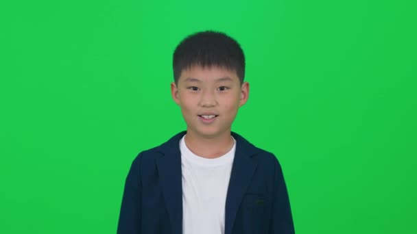 Yeşil Arka Planda Kameraya Bakan Neşeli Asyalı Bir Çocuğun Portresi — Stok video