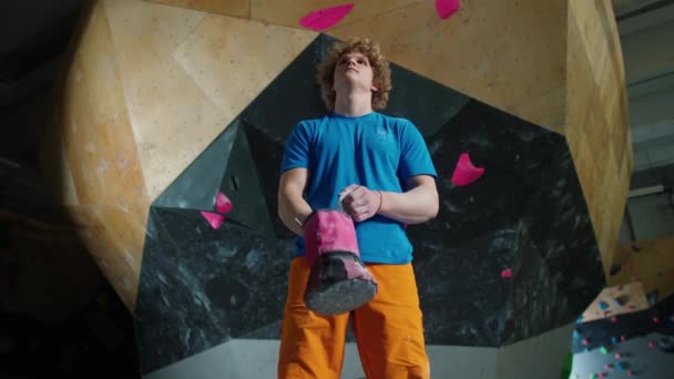 作为一名年轻登山者的画像 小伙子站在攀岩墙的后面 在攀岩前使用了镁合金 — 图库视频影像