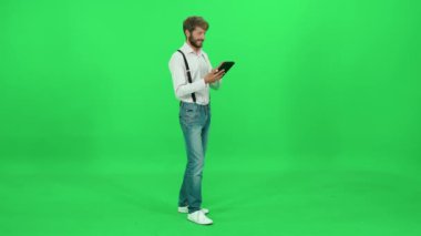 Sanat yönetmeni bir ekran tableti üzerinde çalışır, yazı yazar ve ekrandaki tableti kullanır, yeşil arkaplan, krom anahtar şablonu.