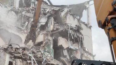 Konut alanındaki bir binanın yıkılması, endüstriyel ekipmanların yardımıyla molozların sökülmesi..