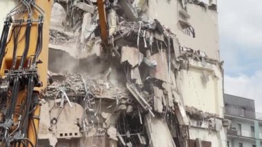 Depremden sonra bir konut binasının sert bir şekilde yıkılması, endüstriyel ekipmanların yardımıyla molozların sökülmesi, kazıcının hidrolik pençesinin binayı yıkması..