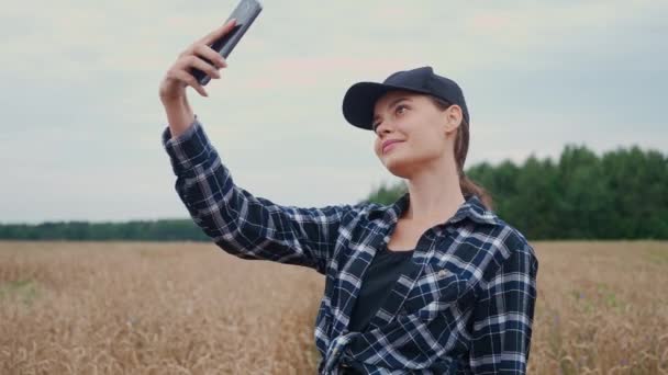 カントリーサイド 美しい女性農家は ライの分野に立って スマートフォンでセルフィーの写真を撮ります 植物を調査 — ストック動画