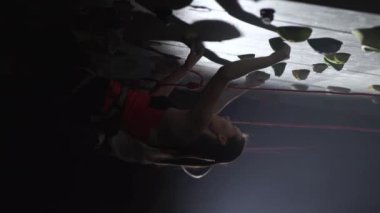 Dikey video, profesyonel tırmanışçılar dik bir duvarda eğitim görüyor, kaya tırmanışı yapıyor ve yükseliyor, sigorta kullanıyor, kaya yapıyor..